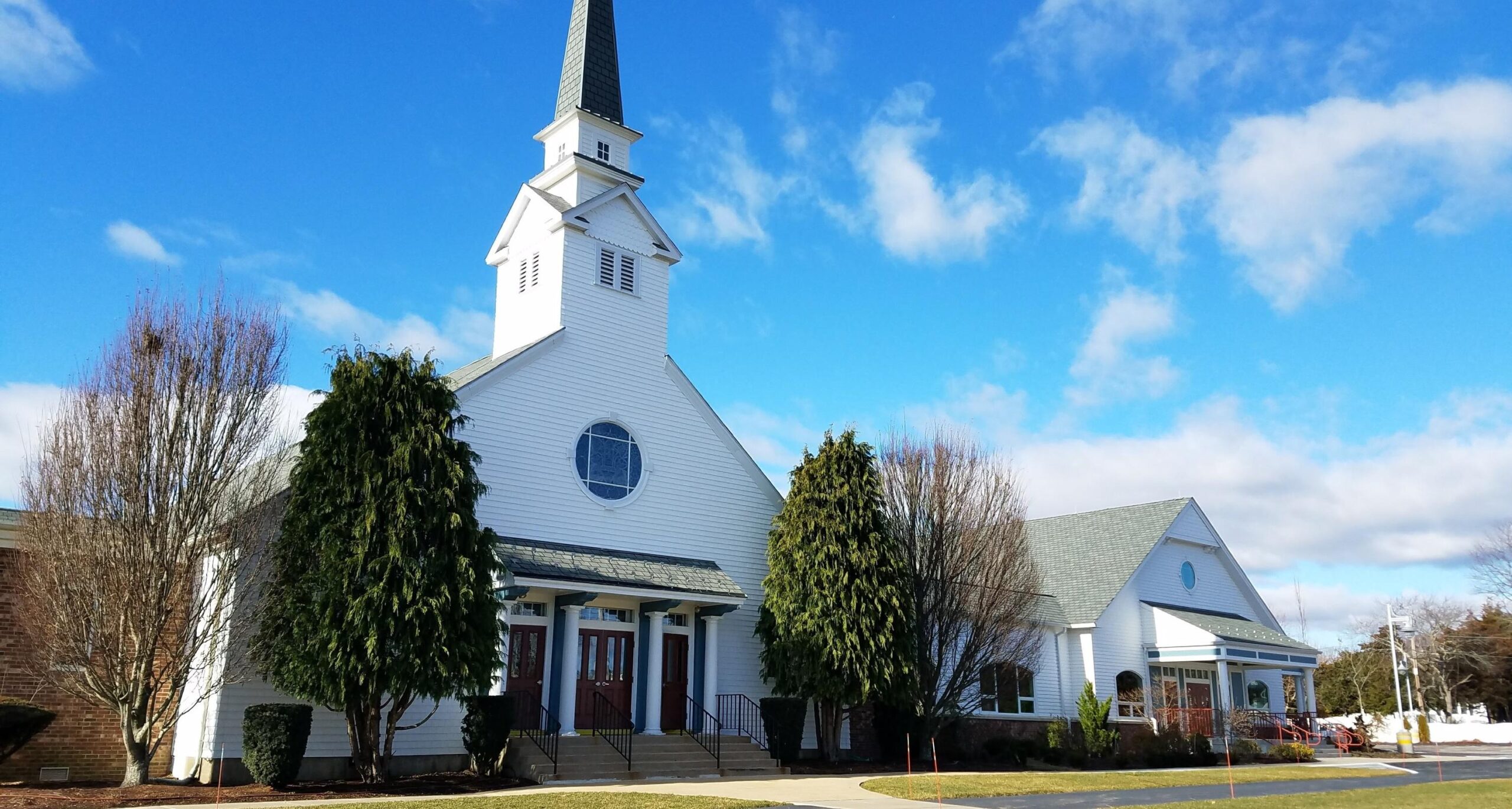White church with a tall steeple beneath a blue sky