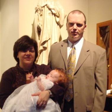 Parents holding a baby at a baptism